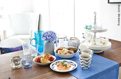 Westwing Woontrends: Gedekte Tafel in de Woonkamer met Servies, Tafellinnen, Etagère, Waxinelichthouders en Glasservies in Wit en Blauw Kleur (Foto Westwing  op DroomHome.nl)