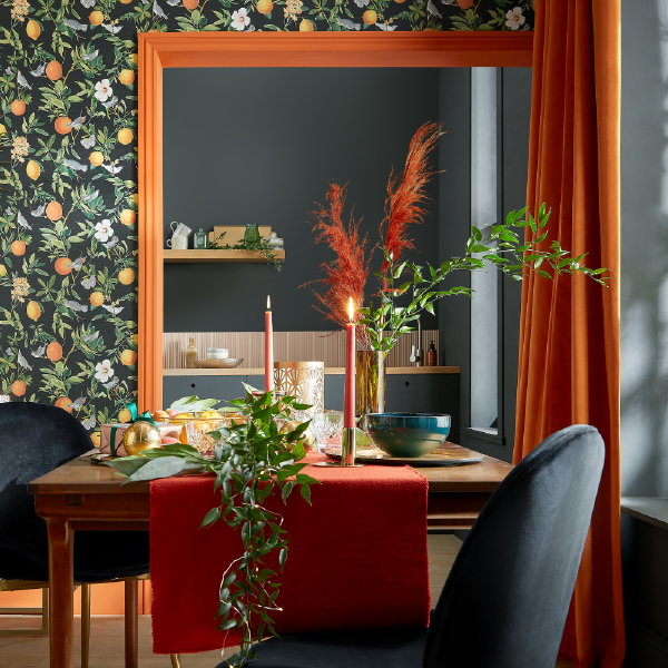 Graham & Brown Kersttrend 2023: Zest of Christmas – Speelse kersttrend met Graham & Brown behang Amalfi Umore met citrusvruchten dessin en oranje pluimen en groene kersttakken (Foto: Graham and Brown  op DroomHome.nl)