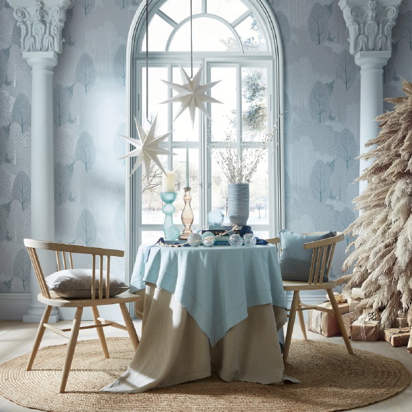 Graham & Brown Kersttrend 2023: Jack Frost – Pastel blauwe kersttrend met Graham & Brown behang Scandiscape Winter & sneeuwwitte kerststerren en kerstboom (Foto: Graham and Brown  op DroomHome.nl)