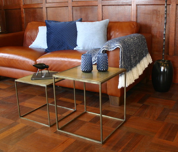 Stoere en Stijlvolle HEMA Woonaccessoires in Blauw – HEMA Kussenhoezen, Plaid op Cognac Kleurige Bank en Vazen, Normann Copenhagen Shorebird en Moooi Notebook op Koperkleurige Bijzettafels. (Foto door DroomHome.nl)